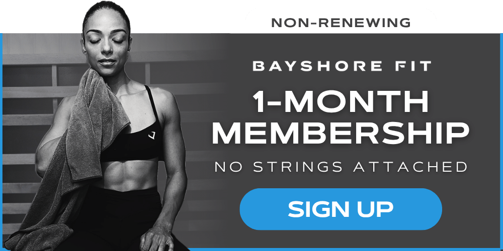 Woman with a towel over her shoulder after a workout, promoting Bayshore Fit's 1-month membership with no long-term commitment.
